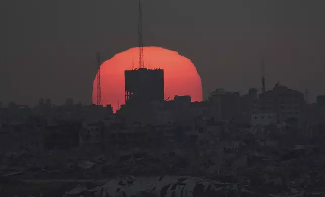 The sun sets over damaged buildings in the Gaza Strip, seen from southern Israel, Tuesday, July 1, 2025. (AP Photo/Ariel Schalit)