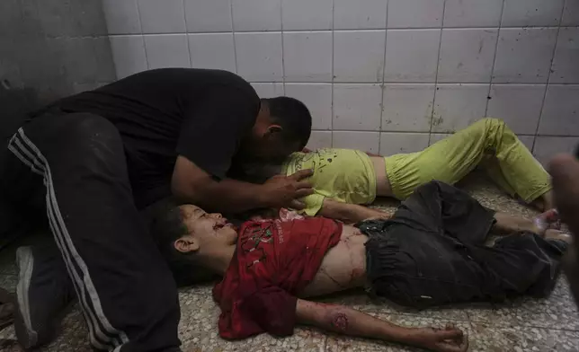 EDS NOTE: GRAPHIC CONTENT - Abdel Hadi Bashir mourns over the bodies of his two daughters, Sabah and Mira who were killed in an Israeli army airstrike of the Gaza Strip, at the Al-Aqsa Hospital morgue in Deir al-Balah, Wednesday, July 2, 2025. (AP Photo/Abdel Kareem Hana)