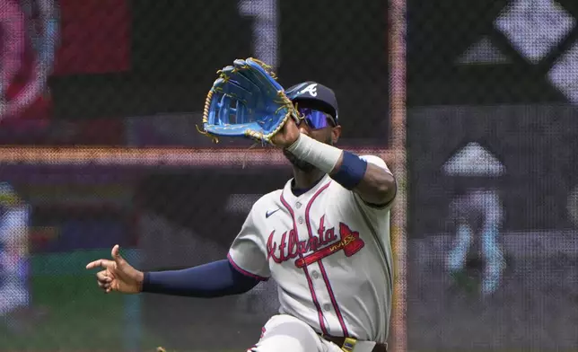 Atlanta Braves left fielder Jurickson Profar catches a fly ball for the out on Kansas City Royals' Vinnie Pasquantino during the fourth inning of a baseball game Wednesday, July 30, 2025, in Kansas City, Mo. (AP Photo/Charlie Riedel)