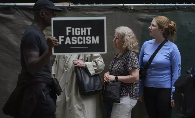 Pedestrians stand aside as anti-Trump, anti-fascism protesters march past as part of the "Good Trouble Lives On" national day of action, in Chicago, Thursday, July 17, 2025. (AP Photo/Erin Hooley)