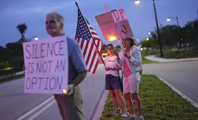 Protesters hold signs during a rally near President Donald Trump's Mar-a-Lago estate in Palm Beach, Fla., as part of the "Good Trouble Lives On" national day of action, Thursday, July 17, 2025. (AP Photo/Rebecca Blackwell)