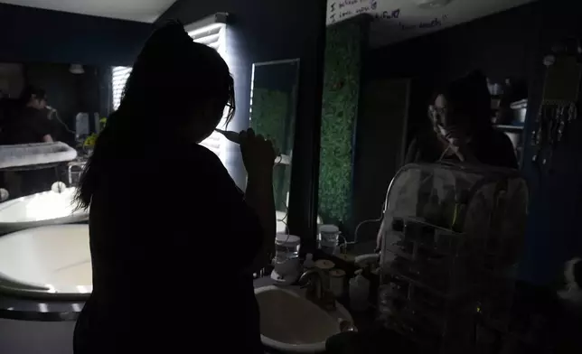 Victoria Silva brushes their teeth with filtered water Wednesday, Feb. 12, 2025, in Fort Collins, Colo. (AP Photo/Brittany Peterson)