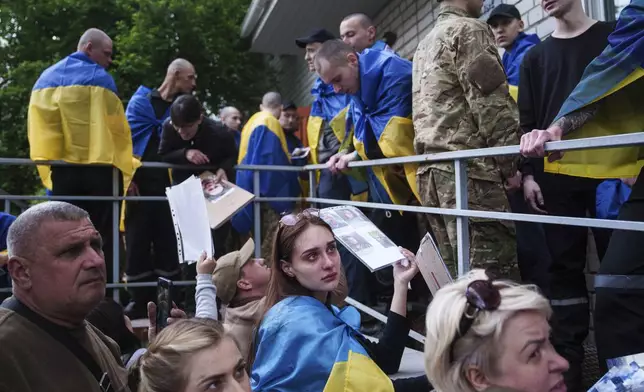 FILE - Relatives of missing and imprisoned Ukrainian soldiers show photographs to servicemen returning from captivity in a POW exchange in Ukraine, Tuesday, May 6, 2025. (AP Photo/Evgeniy Maloletka, File)