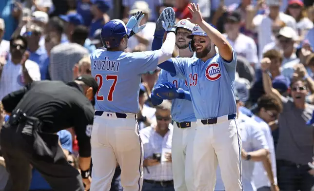 Chicago Cubs' Seiya Suzuki (27) celebrates at home plate with teammate Michael Busch, right, after hitting a three-run home run during the first inning of a baseball game against the Boston Red Sox, Friday, July 18, 2025, in Chicago. (AP Photo/Paul Beaty)