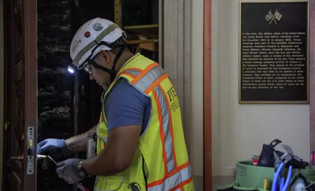 A plaque, discussing the historical significance of the space is visible near a worker in the main two-story board room as renovations continue on the Federal Reserve, Thursday, July 24, 2025, in Washington. (Andrew Harnik/Pool Photo via AP)