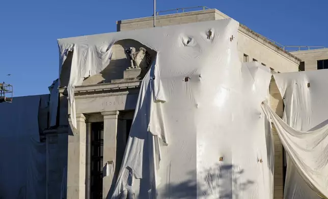 FILE - The sculpture of an eagle looks out from behind protective construction wrapping on the facade as the Federal Reserve Board Building undergoes both interior and exterior renovations, in Washington, Monday, Oct. 23, 2023. (AP Photo/J. Scott Applewhite, File)