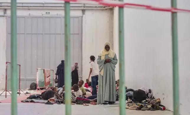 A woman prays as migrants from Africa rest in Agia port, Chania, Crete island, Greece, Monday, July 7, 2025. (AP Photo/Giannis Angelakis)