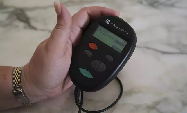 Brandy Ellis checks the battery levels of a pacemaker-like device that was installed in her chest as part of an experimental treatment for depression, on Thursday, July 24, 2025, in Delray Beach, Fla. (AP Photo/Marta Lavandier)