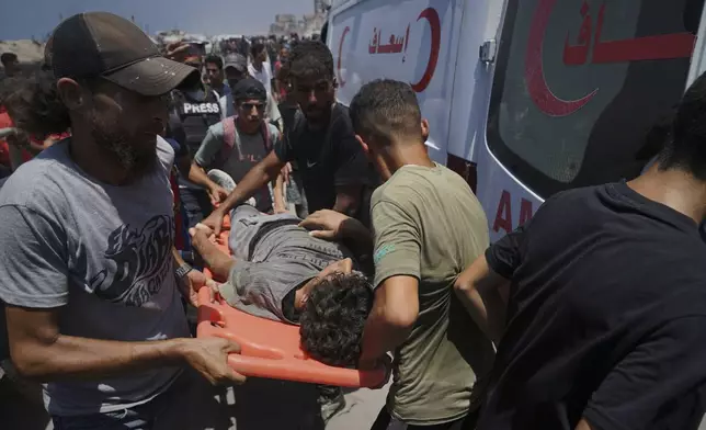 Injured Palestinians are transferred to an ambulance after being wounded while waiting for aid arriving from the northern Gaza Strip, in Gaza City, Tuesday, July 22, 2025. (AP Photo/Jehad Alshrafi)