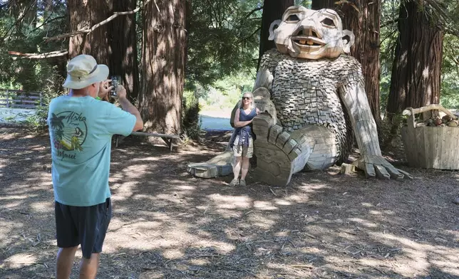 People take pictures alongside a giant troll sculpture created by the Danish recycle artist Thomas Dambo and his team that's part of an installation of six sculptures called "Trolls Save the Humans" on display at the historic estate Filoli, Saturday, July 5, 2025, in Woodside, Calif. (AP Photo/Terry Chea)