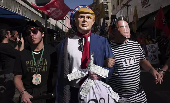 Protesters dressed as police escorting U.S. President Donald Trump and former president of Brazil Jair Bolsonaro demonstrate against Trump's announcement of 50% tariffs on Brazilian goods and against U.S. report that cited counterfeit product sales in Brazil, in Sao Paulo, Friday, July 18, 2025. (AP Photo/Ettore Chiereguini)
