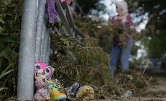 Lost items sit at a bridge as a volunteer cleans up debris on Tuesday, July 8, 2025, after a flash flood swept through the area in Kerrville, Texas. (AP Photo/Ashley Landis)