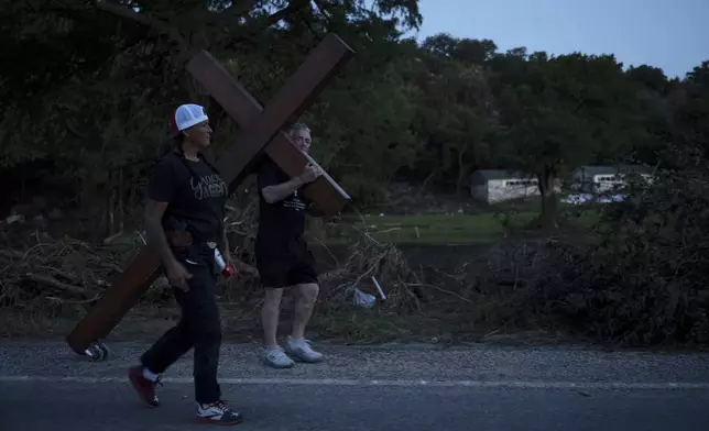 Disaster relief chaplain Sandi Gilmer, left, and Dan Beazley search for a permanent place for Beazley's large cross in memory of flooding victims on Tuesday, July 8, 2025, near Camp Mystic in Hunt, Texas, after a flash flood swept through the area. (AP Photo/Eli Hartman)