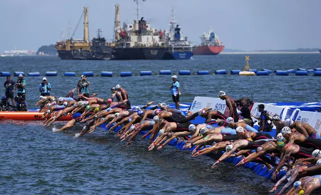 Swimmers dive in at the start of the men's 10km open water swim at the world swimming championships in Singapore, Wednesday, July 16, 2025. (AP Photo/Vincent Thian)