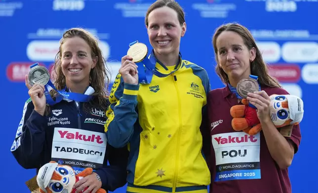 Gold medalist Australia's Moesha Johnson, centre, stands on the podium with silver medalist Ginevra Taddeucci, left, of Italy and bronze medalist Lisa Pou of Monaco following the women's 10km open water swim at the world swimming championships in Singapore, Wednesday, July 16, 2025. (AP Photo/Vincent Thian)
