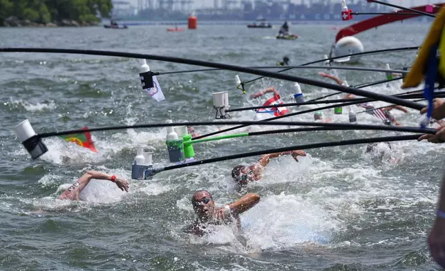 Competitors stop for drinks during the men's 10km open water swim at the world swimming championships in Singapore, Wednesday, July 16, 2025. (AP Photo/Vincent Thian)