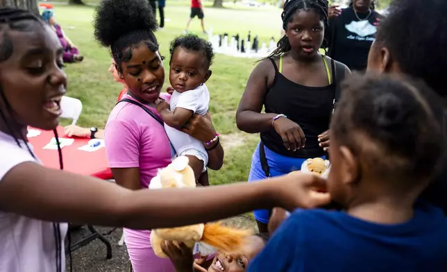 Trinity Wilson, 12, holds her five-month-old cousin, Jaylen, as she and her family walk around the Flint Rx Kids Baby Parade event on July 25, 2025 in on Applewood Campus in Flint, Michigan. The event celebrates the continued impact of Rx Kids on Flint families and babies. (AP Photo/Emily Elconin)