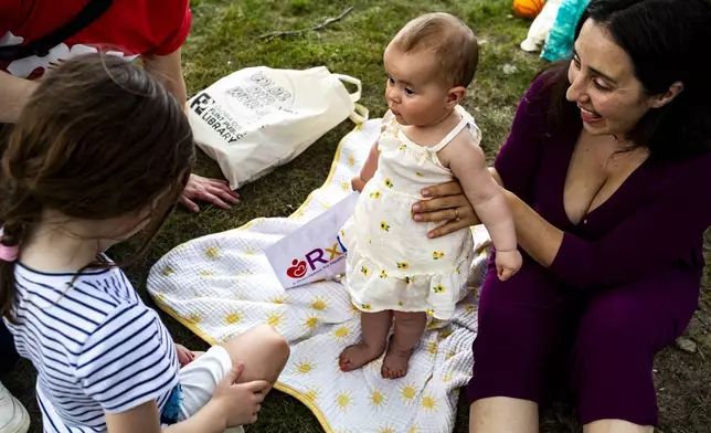 Caroline Doennez smiles as she holds up her nine-month-old daughter, Violet, during the Flint Rx Kids Baby Parade event on July 25, 2025 in on Applewood Campus in Flint, Michigan. The event celebrates the continued impact of Rx Kids on Flint families and babies. (AP Photo/Emily Elconin)