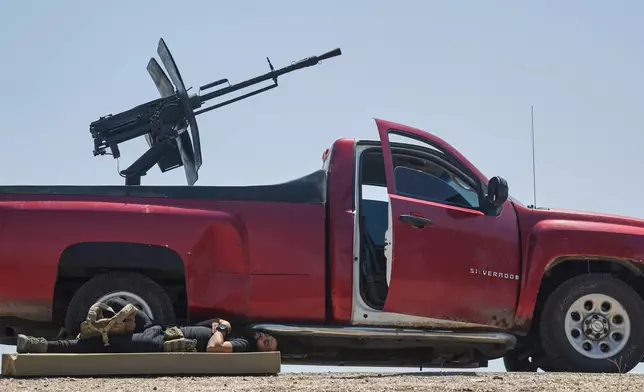 A Syrian security fighter rests in the shade of an armed pickup truck on the outskirts of Sweida province, Syria, Saturday, July 19, 2025. (AP Photo/Ghaith Alsayed)