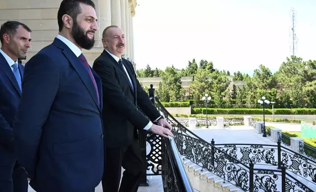 In this photo provided by Azerbaijan's Presidential Press Office, Azerbaijani President Ilham Aliyev, right, and Syria's interim president, Ahmad al-Sharaa, second left, stand on the balcony during their meeting in Baku, Azerbaijan, on Saturday, July 12, 2025. (Azerbaijani Presidential Press Office via AP)