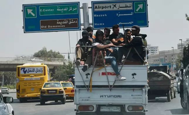 Armed Bedouin fighters ride in the back of a pickup truck as they return from the southern province of Sweida to Damascus, Syria, Saturday, July 19, 2025. (AP Photo/Omar Sanadiki)