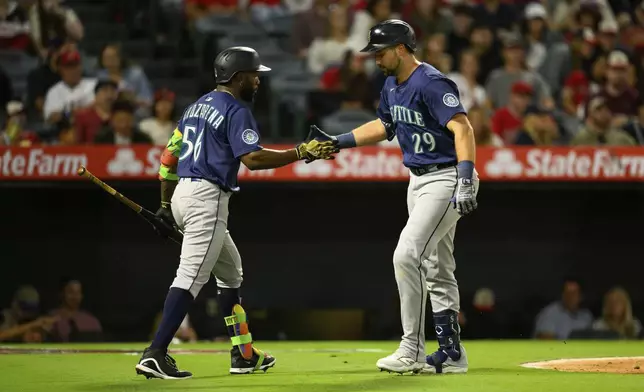 Seattle Mariners' Cal Raleigh, right, is greeted by Randy Arozarena, left, after hitting a home run during the sixth inning of a baseball game against the Los Angeles Angels, Saturday, July 26, 2025, in Anaheim, Calif. (AP Photo/William Liang)