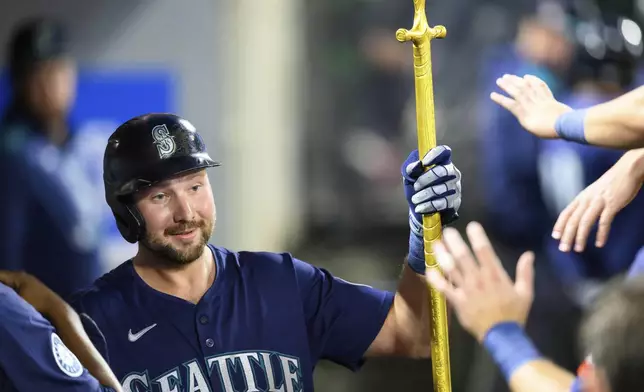 Seattle Mariners' Cal Raleigh is greeted by teammates after hitting a home run during the sixth inning of a baseball game against the Los Angeles Angels, Saturday, July 26, 2025, in Anaheim, Calif. (AP Photo/William Liang)
