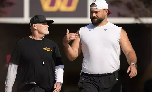 Washington Commanders head coach Dan Quinn walks with guard Sam Cosmi before practice at the team's NFL football training camp, Thursday, July 24, 2025, in Ashburn, Va. (AP Photo/Mark Schiefelbein)