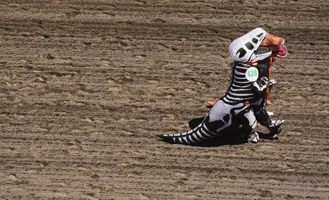 Farrah Downing, front, and Julie David, back, hold hands as they participate during the "T-Rex World Championship Races" at Emerald Downs, Sunday, June 29, 2025, in Auburn, Wash. (AP Photo/Lindsey Wasson)