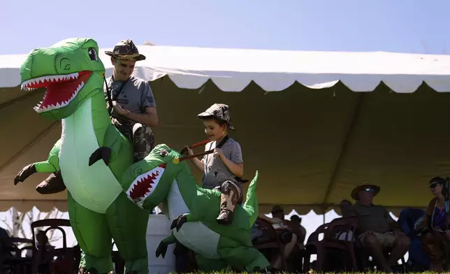 Jordan Evans, left, wears a matching costume with son Micah Evans, 5, during the "T-Rex World Championship Races" at Emerald Downs, Sunday, June 29, 2025, in Auburn, Wash. (AP Photo/Lindsey Wasson)
