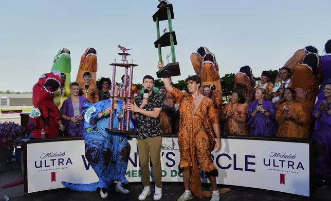 Women's winner Linsey Lovrovich, of Gig Harbor, Wash., at left, and men's winner Andrew Stuber of Houston at right, celebrate with their trophies after participating in the "T-Rex World Championship Races" at Emerald Downs, Sunday, June 29, 2025, in Auburn, Wash. (AP Photo/Lindsey Wasson)