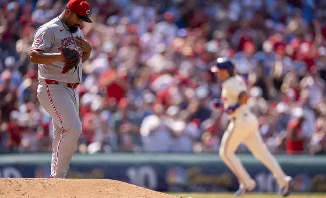 Cincinnati Reds relief pitcher Tony Santillan, left, reacts as Philadelphia Phillies' Bryson Stott, right, rounds the bases after hitting a two-run home run during the eighth inning of a baseball game, Sunday, July 6, 2025, in Philadelphia. (AP Photo/Chris Szagola)