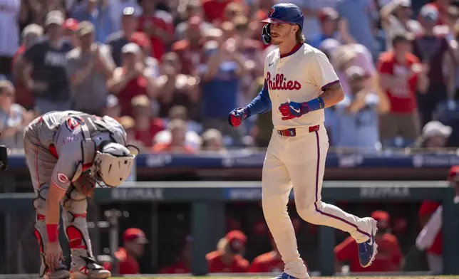 Philadelphia Phillies' Bryson Stott, right, scores on his two-run home run as Cincinnati Reds catcher Tyler Stephenson, left, looks down during the eighth inning of a baseball game, Sunday, July 6, 2025, in Philadelphia. (AP Photo/Chris Szagola)