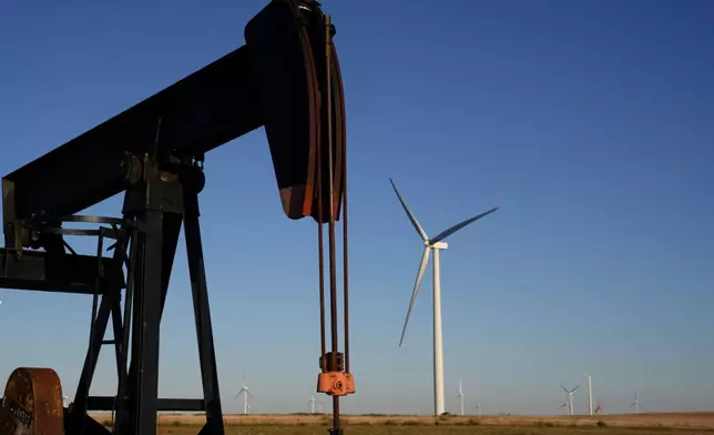 FILE - Pumpjacks operate in the foreground while a wind turbines at the Buckeye Wind Energy wind farm rise in the distance Monday, Sept. 30, 2024, near Hays, Kan. (AP Photo/Charlie Riedel, File)