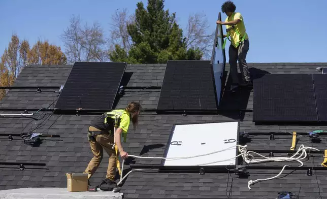 FILE - Theodore Tanczuk, left, and Brayan Santos, right, of solar installer YellowLite, put panels on the roof of a home in Lakewood, Ohio, April 16, 2025. (AP Photo/Sue Ogrocki, File)