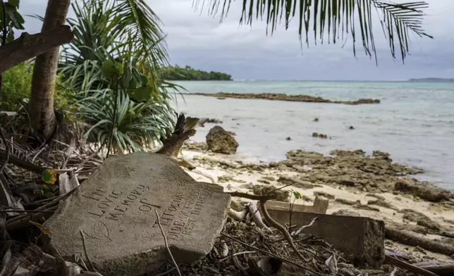 A gravestone lies just feet from the shoreline on Pele Island, Vanuatu, Friday, July 18, 2025. (AP Photo/Annika Hammerschlag)