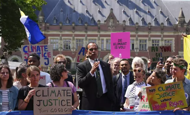 Ralph Regenvanu, Vanuatu's minister for climate change, speaks surrounded by demonstrators as he arrives to the International Court of Justice ahead of an advisory opinion on what legal obligations nations have to address climate change and what consequences they may face if they don't, Wednesday, July 23, 2025, in The Hague, Netherlands. (AP Photo/Peter Dejong)
