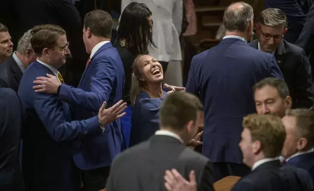 Rep. Marjorie Taylor-Greene, R-Ga., center, laughs as Speaker of the House Mike Johnson, R-La., right, is greeted in the House chamber during final passage of President Donald Trump's signature bill of tax breaks and spending cuts, at the Capitol, Thursday, July 3, 2025, in Washington. (AP Photo/Rod Lamkey, Jr.)