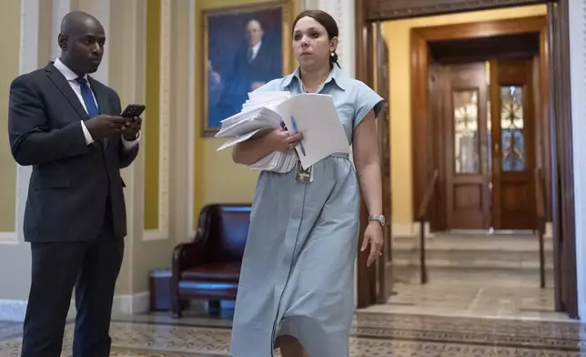 Megan Owen, chief counsel to Senate Majority Leader John Thune, relays papers from the chamber as Thune struggles with Republicans opposed to President Donald Trump's signature bill of big tax breaks and spending cuts, at the Capitol in Washington, Tuesday, July 1, 2025. (AP Photo/J. Scott Applewhite)
