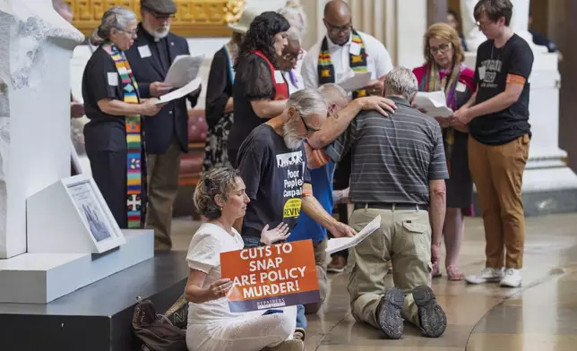 Activists organized by the Repairers of the Breach demonstrate their opposition to President Donald Trump's tax breaks and spending cuts as they gather in the Capitol Rotunda to pray and submit to arrest by U.S. Capitol Police, in Washington, Monday, June 30, 2025. (AP Photo/J. Scott Applewhite)