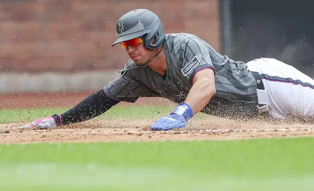 New York Mets' Tyrone Taylor slides home to score in the third inning of a baseball game against the Cincinnati Reds, Sunday, July 20, 2025, in New York. (AP Photo/Heather Khalifa)