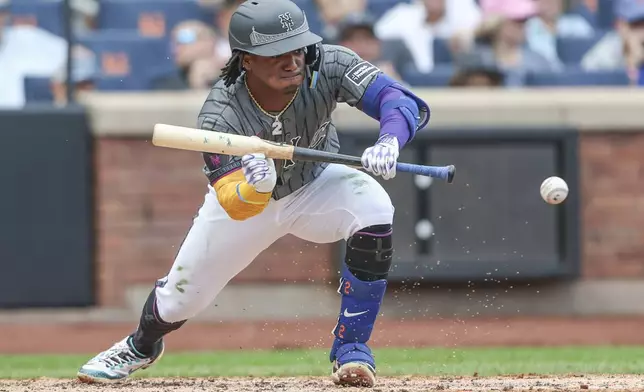 New York Mets' Luisangel Acuña (2) hits a sacrifice bunt in the third inning of a baseball game against the Cincinnati Reds, Sunday, July 20, 2025, in New York. (AP Photo/Heather Khalifa)