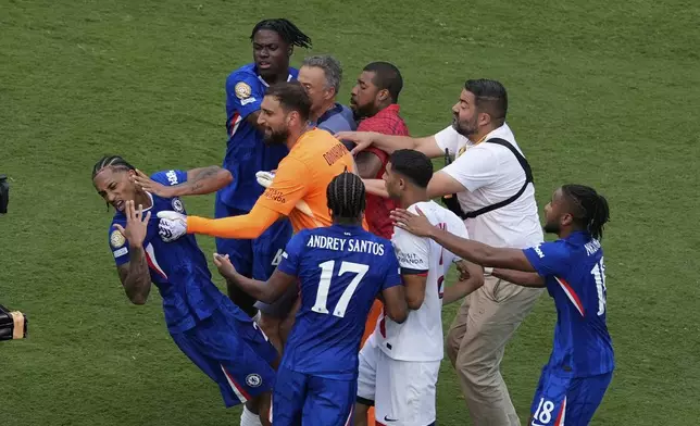 Chelsea's Joao Pedro, left, is attacked by Paris Saint-Germain's goalkeeper Gianluigi Donnarumma and coach Luis Enrique at the end of the Club World Cup final soccer match between Chelsea and PSG in East Rutherford, N.J., Sunday, July 13, 2025. (AP Photo/Pamela Smith)