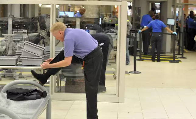 FILE - A traveler removes his shoes at Hartsfield-Jackson Atlanta International Airport on Wednesday, Jan. 15, 2014 in Atlanta. (Kent D. Johnson/Atlanta Journal-Constitution via AP, File)