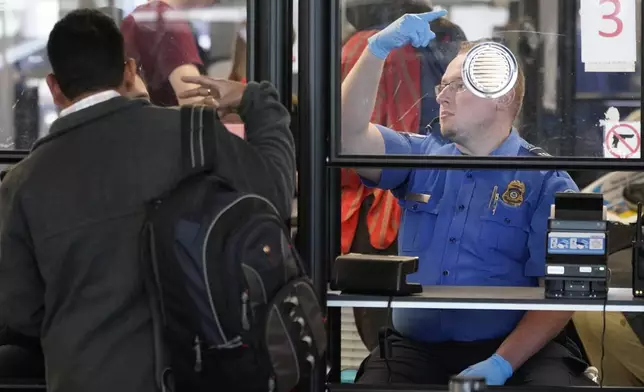 FILE - A Transportation Security Administration agent signals for the next airline passenger in line at a security checkpoint in Chicago's O'Hare International Airport Friday, May 26, 2023. (AP Photo/Charles Rex Arbogast, File)