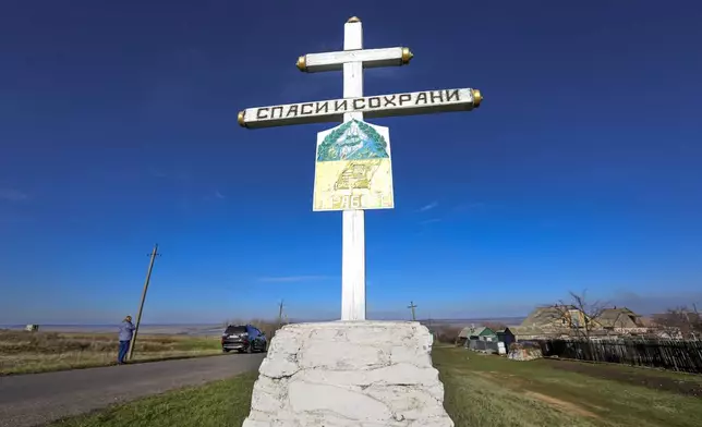 FILE - An Orthodox cross with a sign reading Save and Guard, is seen with a memorial to the victims of the Malaysian Airlines MH17 plane crash, near the village of Hrabove, Russian-controlled Donetsk region of eastern Ukraine, Nov. 15, 2022. (AP Photo, File)