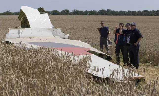 FILE - Australian and Dutch investigators examine a piece of the Malaysia Airlines Flight 17 plane, near the village of Hrabove, Russian-controlled Donetsk region of eastern Ukraine in Aug. 1, 2014. (AP Photo, File)