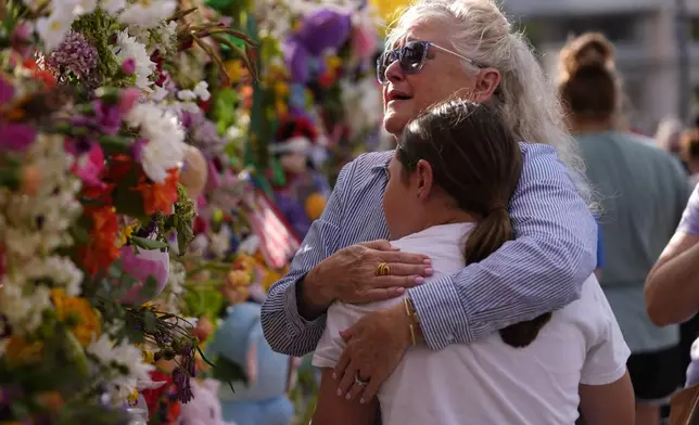 Mourners from Kerrville, Julia Mora embraces her granddaughter, Isla Meyer during a vigil for flood victims on Friday, July 11, 2025, in Kerrville, Texas. (AP Photo/Gerald Herbert)