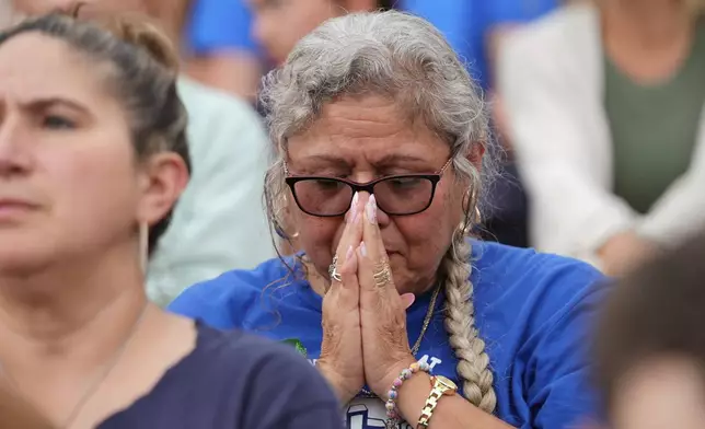 A woman prays during a vigil for flooding victims at Tivy Antler Stadium on Wednesday, July 9, 2025, in Kerrville, Texas. (AP Photo/Gerald Herbert)