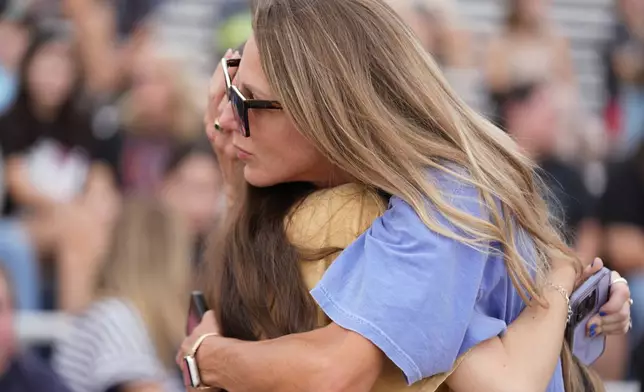 Kate McKee, right, a teacher at Hal Peterson Middle School, hugs an attendee during a vigil for flooding victims at Tivy Antler Stadium on Wednesday, July 9, 2025, in Kerrville, Texas. (AP Photo/Gerald Herbert)